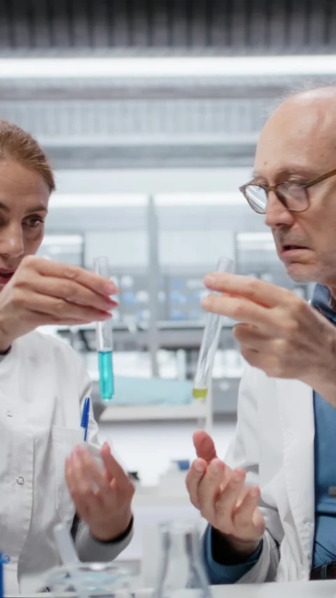 Vertical video Lab team leader teaching intern to analyze liquid polymer Stock Footage 327170184