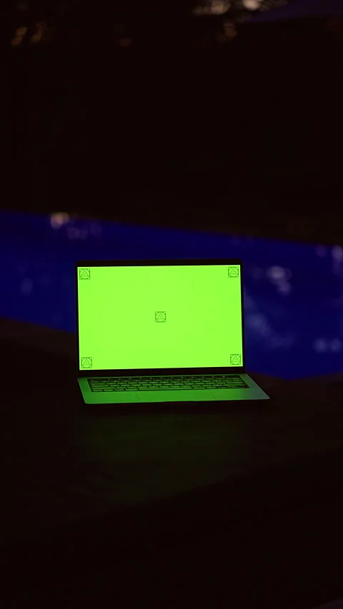 Vertical video. Laptop With Green Screen Mockup Beside a Tropical Pool at Night, Stock Footage 336554899