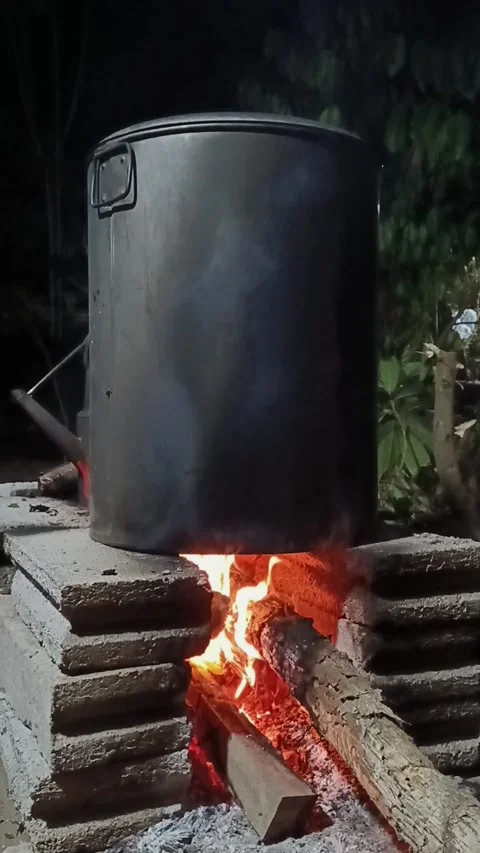 Vertical video of large cooking pot boiling over open wood fire outdoors Stock Footage 346673044