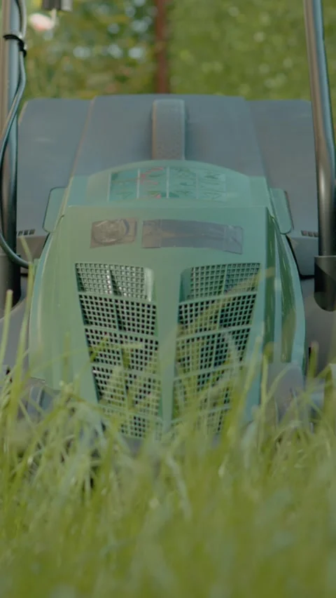 Vertical video Lawn mower ready for grass cutting on terrace overgrown with tall Stock Footage 323357885