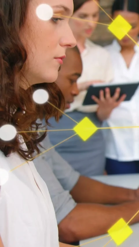 Vertical video: Lead at desk typing while team viewing tablet, causing node map Stock Footage 333289721