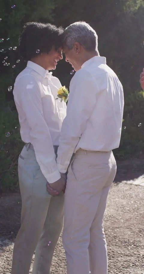 Vertical video: Leaning couple in shirts holding hands sharing joy on path Stock Footage 346721787