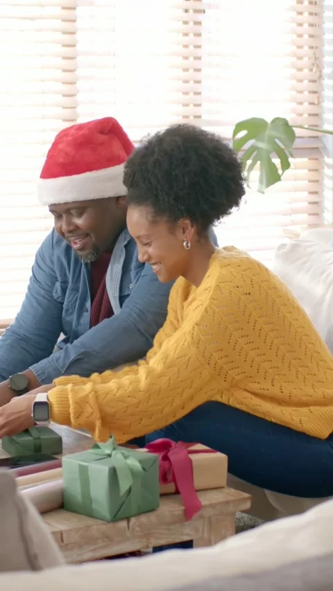 Vertical video: Leaning forward couple tying ribbons on coffee table for Stock Footage 348273215
