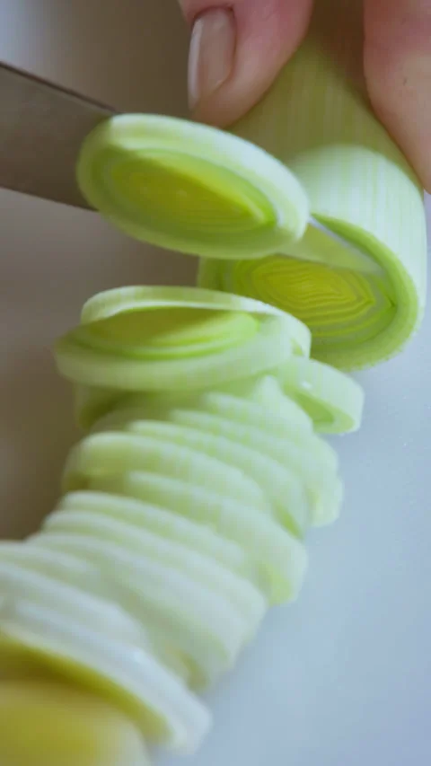 Vertical video of Leek Cutting Process. Slow Motion. White kitchen board. Stock Footage 296156706