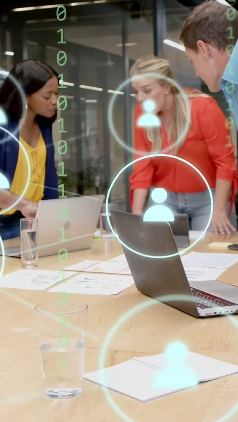 Vertical video: Left woman tapping laptop, user icons drifting over table, tech Stock Footage 334792886
