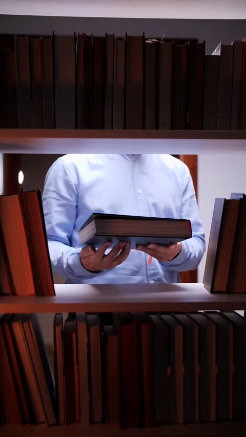 Vertical video Librarian holding book between bookshelves in library Stock Footage 311022836