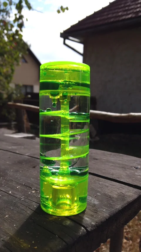 Vertical video of liquid motion bubbler timer on outdoor wooden table Видео 345214470
