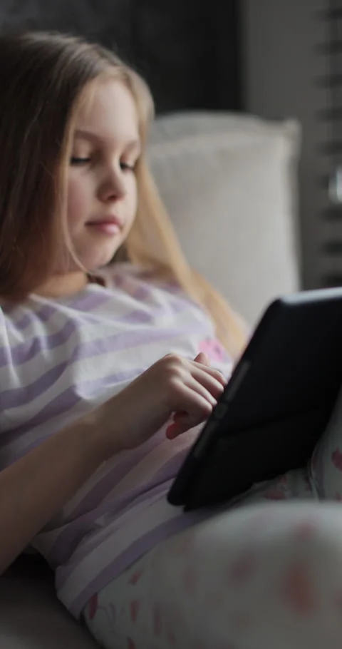 Vertical video. Little girl using digital tablet at home. Child on social media. 動画素材 335643905