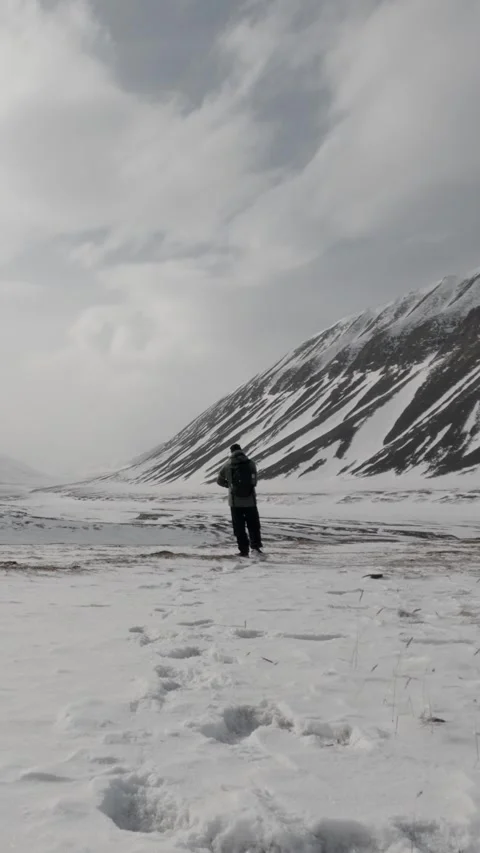 Vertical Video of Lone Hiker Crossing Remote Snowy Landscape in Svalbard Stock Footage 340037079