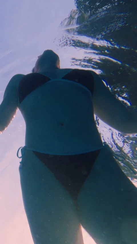 Vertical video. Low Angle Underwater Shot Of Woman Near Pool Surface With Sunlig 動画素材 326910990
