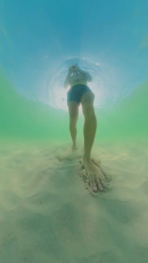 Vertical video. Low Angle Underwater View Person Walking On Sandy Bottom With Su Stock Footage 333264652