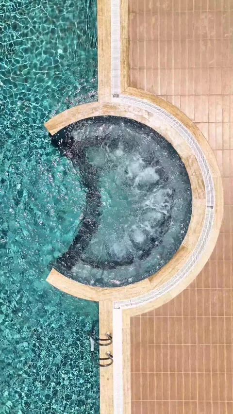 Vertical Video: Luxurious Pool with Clear Azure Water and a Jacuzzi for Ultimate Stock Footage 297712567
