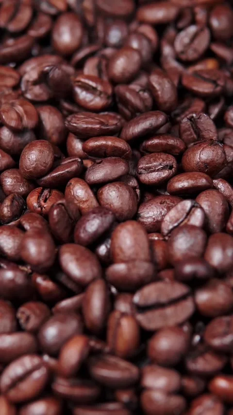 Vertical video macro shot of rich dark roasted coffee beans texture filling Stock Footage 345211951