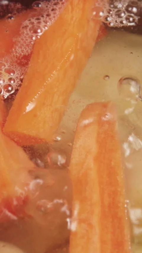 Vertical video macro view of fresh carrots and broccoli boiling in bubbling Stock Footage 345212424