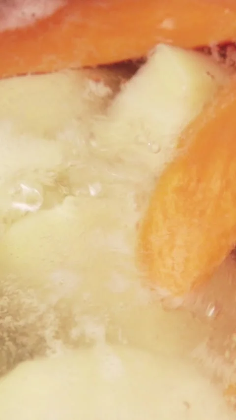 Vertical video macro view of fresh carrots and broccoli boiling in bubbling Stock Footage 345212444