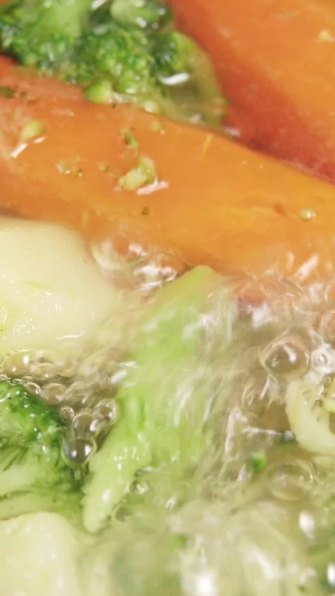 Vertical video macro view of fresh carrots and broccoli boiling in bubbling.. Stock Footage 346399151