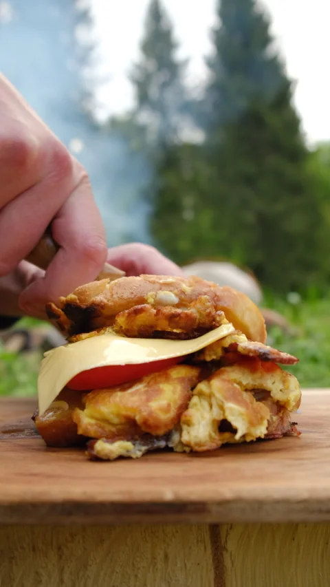 Vertical video of male hands using knife cutting hot sandwich near bonfire Stock Footage 274384239