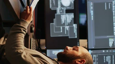 Vertical video: Male IT engineer analyzing web data on clipboard papers and Stock Footage 222210397