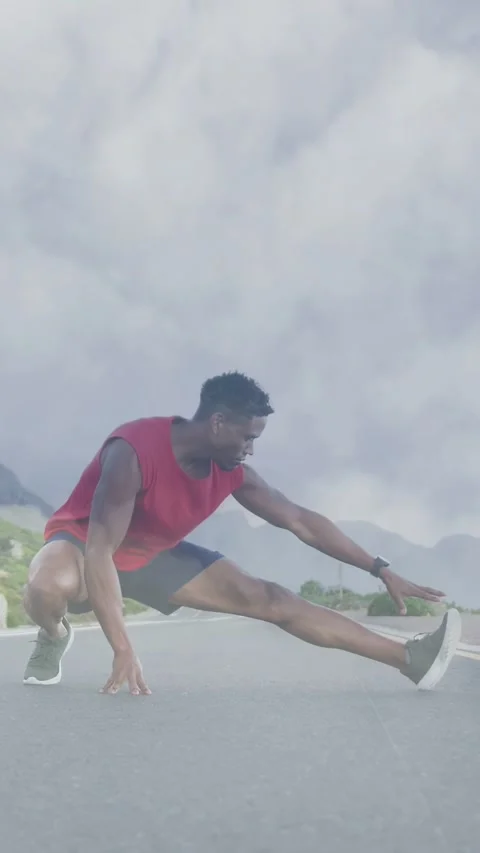 Vertical video: Male runner performing deep side lunge on mountain road while Stock Footage 334296211