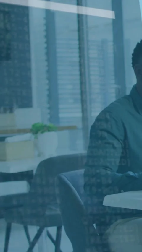Vertical video: Man analyzing data at table in tech office, camera panning Stock Footage 332278183
