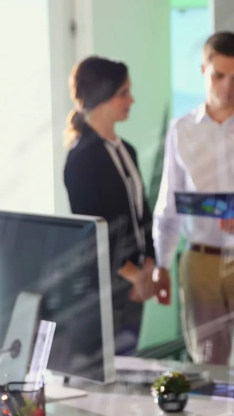 Vertical video: Man angling brochure, woman leaning in and examining chart for Stock Footage 332823478