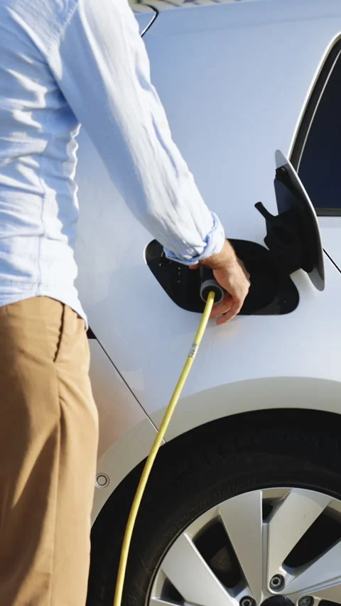 Vertical Video of man attaching power cable to electric car. Electric vehicle Stock Footage 306119190