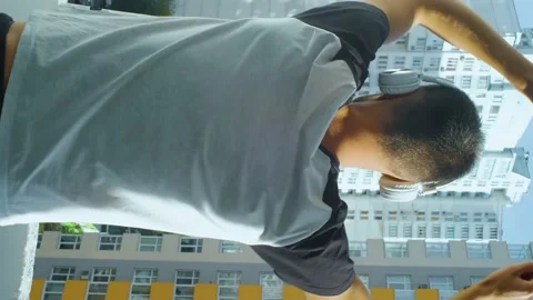 Vertical video of a man back view, dancing at balcony wearing wireless Stock Footage 168716421