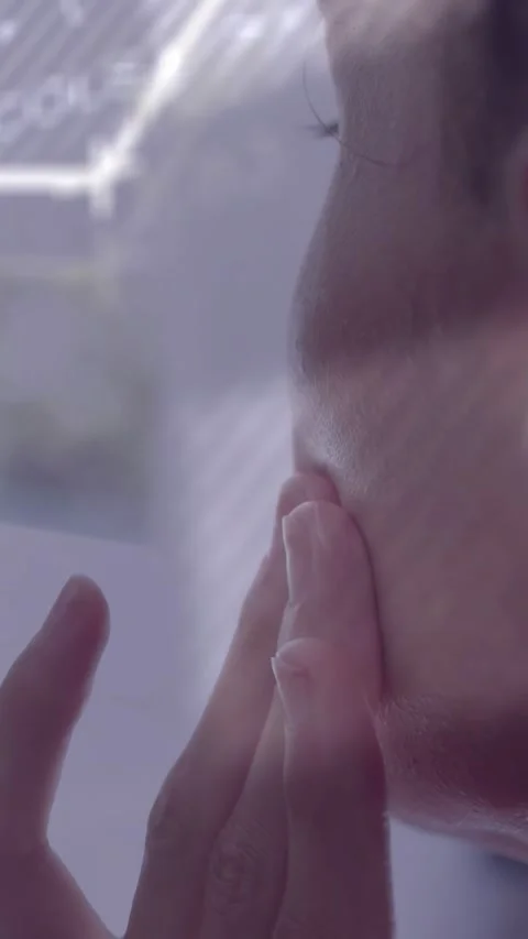 Vertical video: Man bringing hand to face at window pressing jawline reacting to Stock Footage 333821630