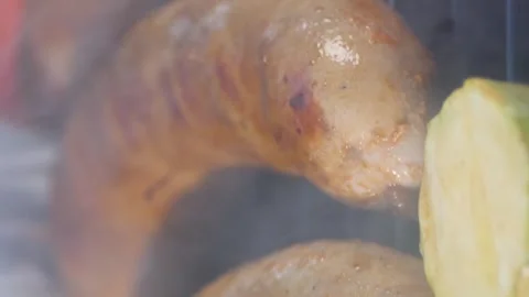 Vertical video. A man brushes grilled sausages with oil. Frying sausages with Stock Footage 267289279