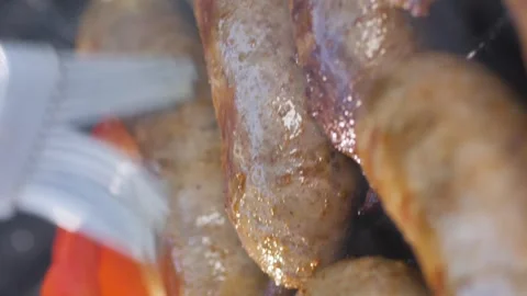 Vertical video. A man brushes grilled sausages with oil. Frying sausages with Video stock 267289557