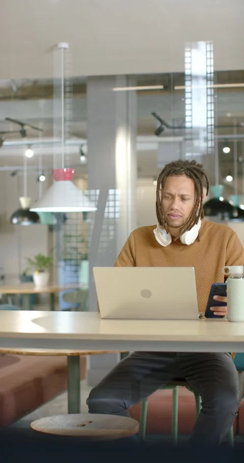 Vertical video: Man checking phone after ping, reading, typing on laptop at Stock Footage 346721515