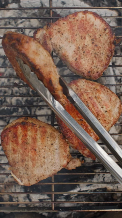Vertical video of man cooking beef steak metal grid on campfire at winter time Stock Footage 297944855