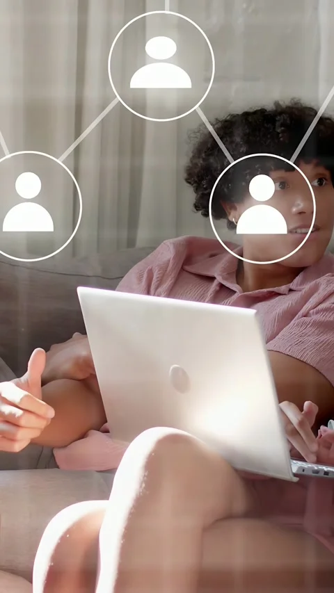 Vertical video: Man on couch holding laptop user icons rising, driving tech work Stock Footage 333658282