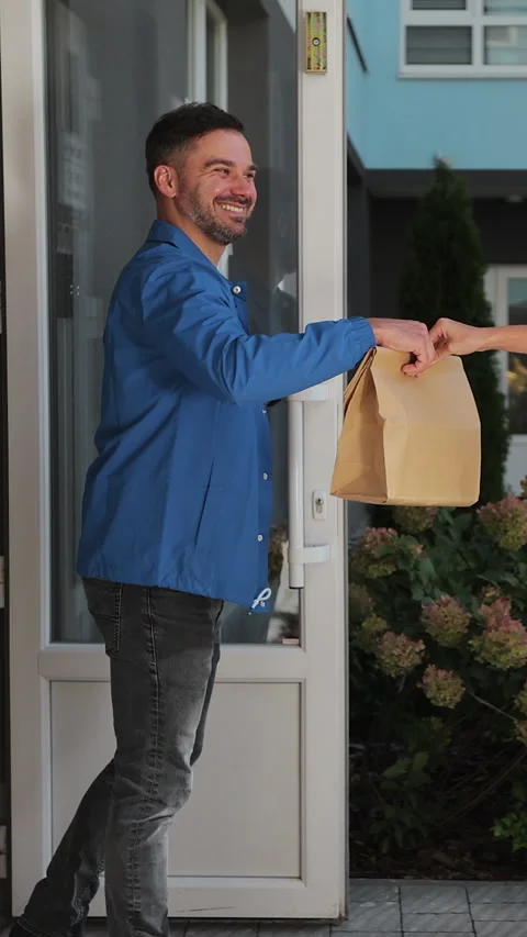 Vertical video. Man customer open door to a food delivery woman Stock Footage 344373585