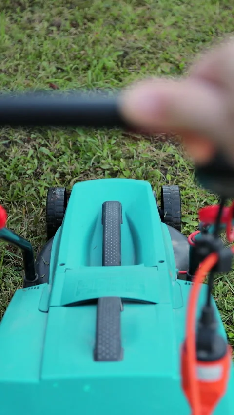 Vertical video Man cuts the grass on the lawn with an electric lawnmower. Stock Footage 339062288