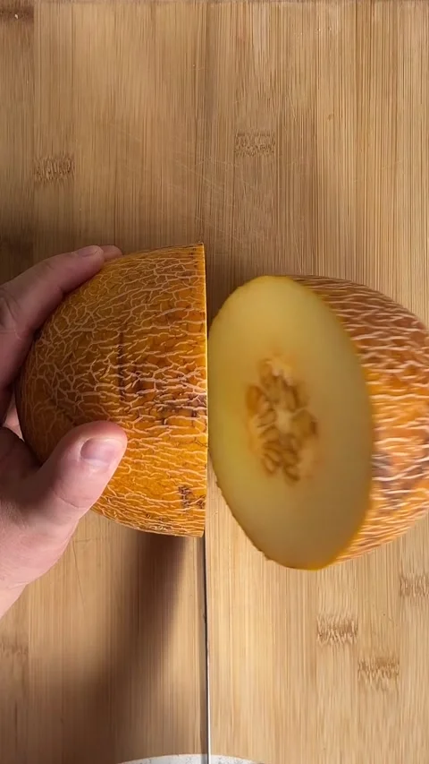 Vertical video. Man cuts sweet fresh raw tasty juicy yellow melon on gray plate Stock Footage 280880291