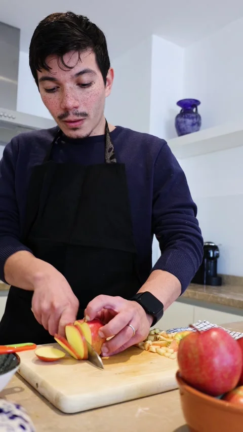 Vertical video of a man cutting apples into slices on a wooden board making.. Stock Footage 297474176