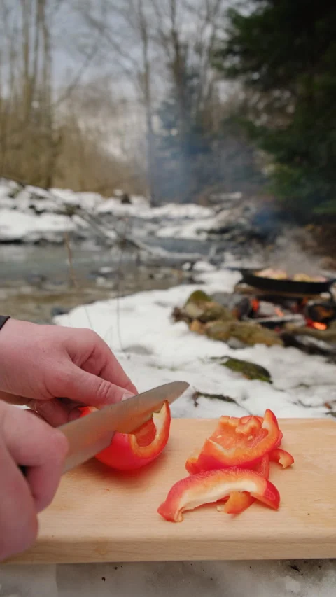 Vertical video of man cutting fresh red peppers near bonfire and mountains river Stock Footage 297961356