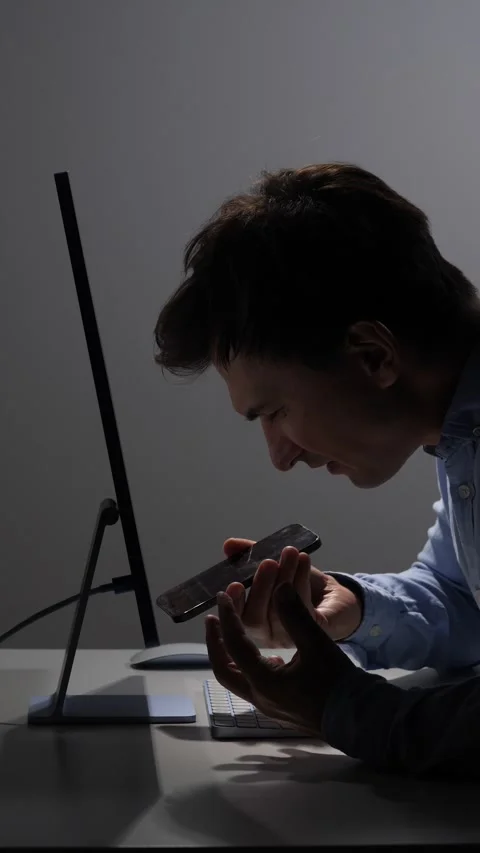 Vertical video man in a dark office setting angrily yelling into his smartphone Stock Footage 342672672