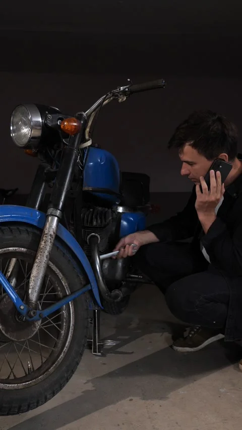 Vertical video man in a dark workshop talking on a phone, while actively Stock Footage 342774852