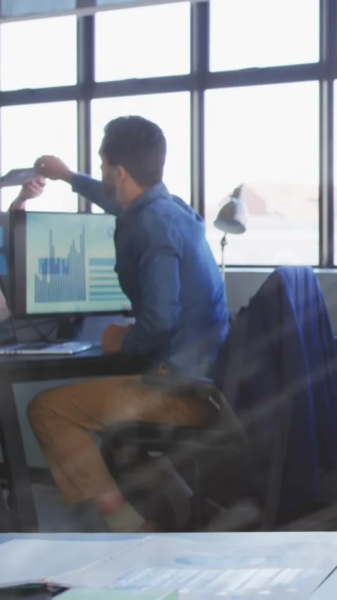 Vertical video: Man at desk taking offered tablet, matching monitor chart and Stock Footage 329875882