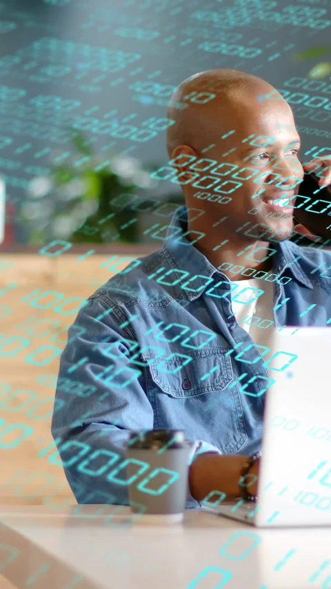 Vertical video: Man at desk taking joyful phone call, smiling with animated tech Stock Footage 333577717