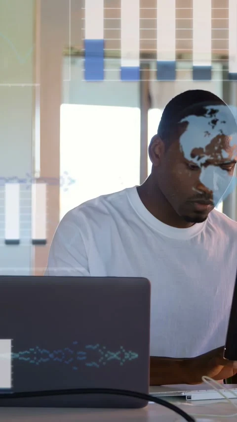 Vertical video: Man at desk typing, causing tech overlays of charts map code for Stock Footage 333556951