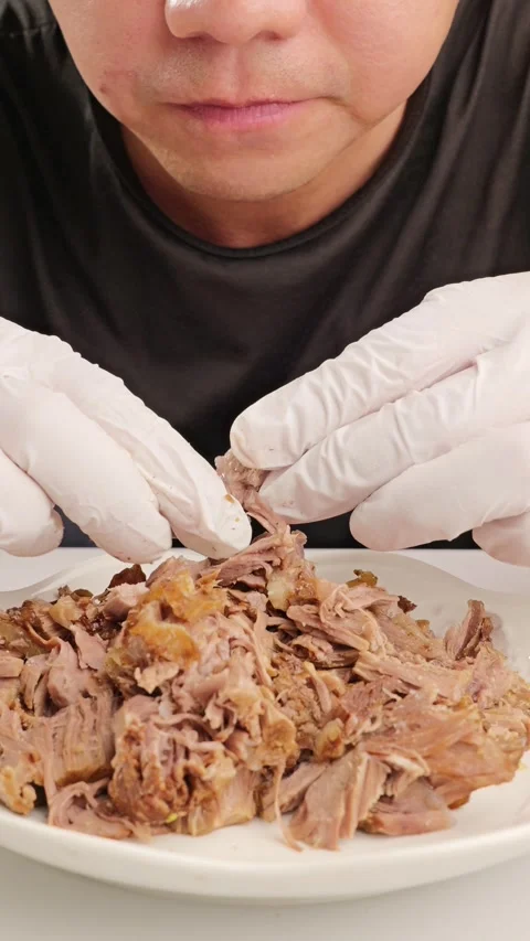 Vertical video: Man eating hand‑torn marinated beef. Stock Footage 343597835