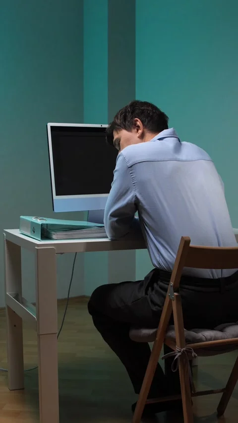 Vertical video man focusing on his work, sitting at a desk with a computer and Stock Footage 345531553