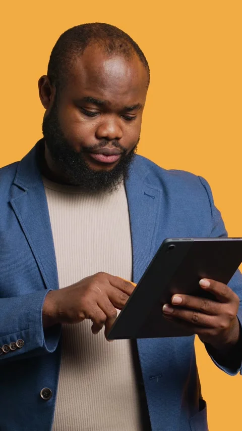 Vertical video Man frowning seeing insufficient funds error on tablet, studio Stock Footage 272835308