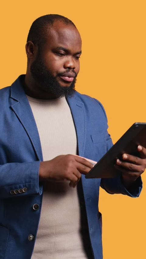 Vertical video Man frowning seeing insufficient funds error on tablet, studio Stock Footage 272836887