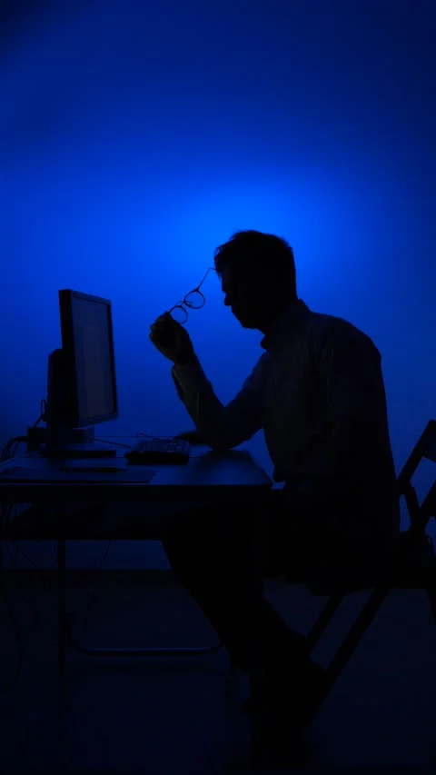 Vertical video Man in glasses in silhouette working late on computer in dark Stock Footage 322910922