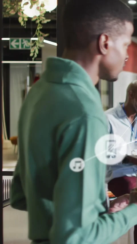 Vertical video: Man in green pullover tapping phone in office, animated icons Stock Footage 330769425