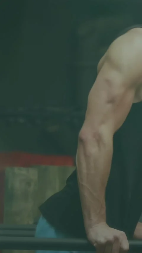 Vertical video: Man gripping parallel bars and performing triceps dip in gym, Stock-Footage 331077566